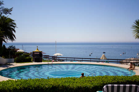Sesimbra, Portugal - CIRCA, July 2021: Swimming pool with sea on the backgroundの写真素材