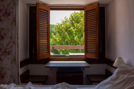 Room with bed and open wooden shuttersの写真素材