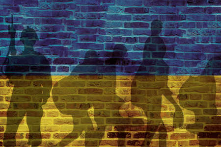 Ukraine flag on wall and shadows of soldier and refugees leaving. Ukraine war conceptの素材 [FY310183636667]