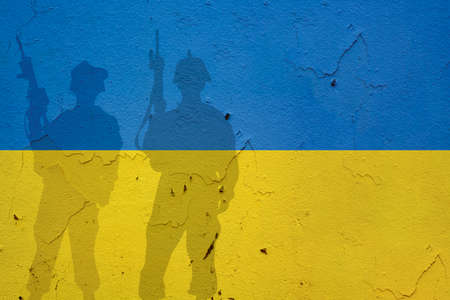 Ukraine flag on wall and shadows of soldiers. Ukraine war conceptの写真素材