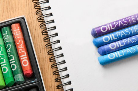 Oil pastel crayons and spiral art sketch book on wooden backgroundの写真素材