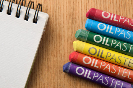 Oil pastel crayons and spiral art sketch book on wooden backgroundの写真素材