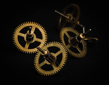 Group of gold metal gearwheels on black background