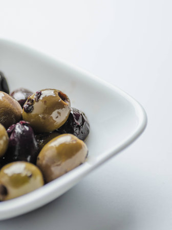 Mixed Mediterranean olives in white bowl on white backgroundの写真素材
