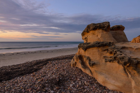 Scenic coastline landscape at sunset with cliff boulders on the beachの写真素材