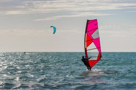 Windsurfer on surfboard slides on waves sea waterfront activity at the beach