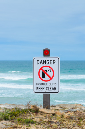 Warning sign danger unstable cliffs keep clear rural coast lineの写真素材