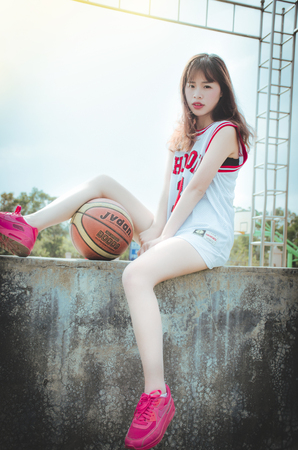 Female sitting on the balcony edge with a basketball in sports outfitのeditorial素材