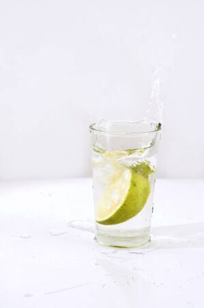 Citrus splash - piece of orange splashing on glass of water isolatedの写真素材