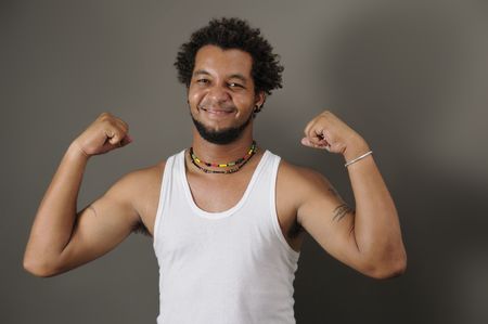 Portrait of young happy latino man showing his strong musclesの写真素材