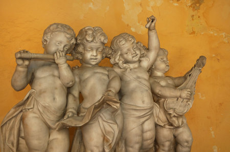 Statue of 4 little angels playing musical instruments against yellow wall - Old Havanaの写真素材