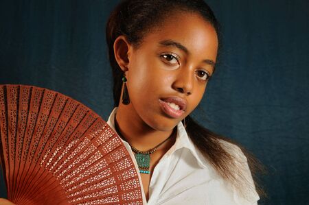 Portrait of young african fashion teenage female with fanの写真素材