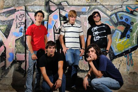 Portrait of 5 trendy teenagers sitting in front of graffiti wallの写真素材