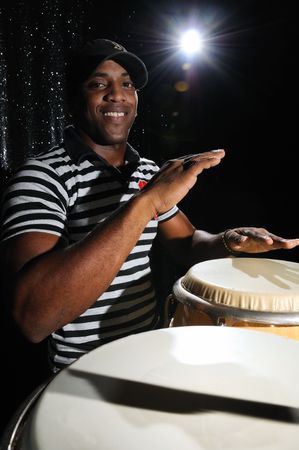 Portrait of young latino percusionist playing african drumsの写真素材