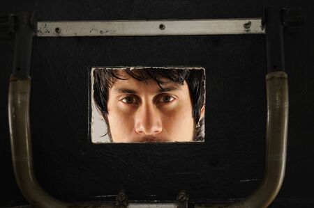 Portrait of a young man looking from a board apertureの写真素材