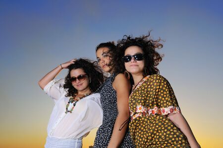 Portrait of three trendy girls posing at sunsetの写真素材