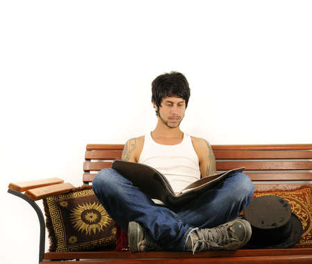 Portrait of young trendy hispanic man reading a magazine - isolatedの写真素材