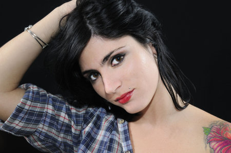 Portrait of young trendy brunette beauty with flower tattoo posing isolated on blackの写真素材