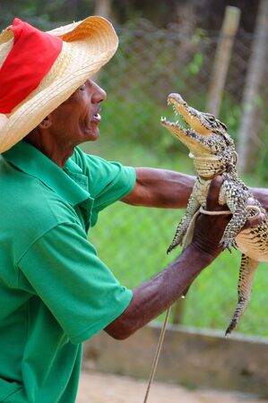 Portrait of a man holding small crocodile in Guama lagoon, cuba. This touristic place holds the rest of a native cuban indian community. Taken circa March 2008.のeditorial素材