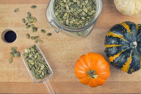 Colorful background with pumpkin seeds and squash over wooden backgroundの写真素材