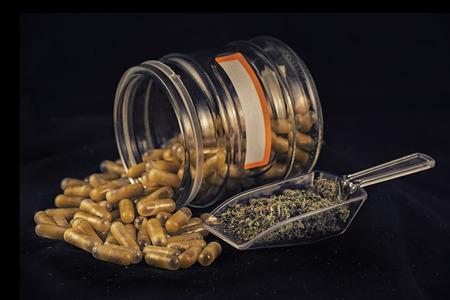 Cannabis extraction capsules infused with shatter and dried marijuana isolated over black backgroundの写真素材