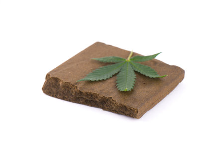 Block of hashish, a medical marijuana concentrate isolated on white with cannabis leaf