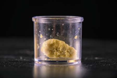 Macro detail of a single piece of marijuana extraction concentrate aka wax crumble on isolated jarの写真素材