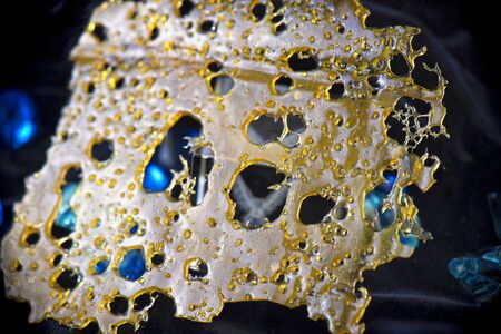 Close up detail of marijuana oil concentrate slab for dabbing aka shatter isolated on black backgroundの写真素材