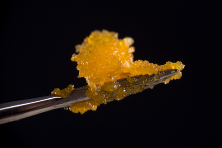 Macro detail of cannabis concentrate live resin (extracted from medical marijuana) isolated over black on a dabbing toolの写真素材