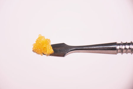 Macro detail of cannabis concentrate live resin (extracted from medical marijuana) isolated over white on a dabbing toolの写真素材