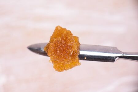 Macro detail of cannabis concentrate live resin (extracted from medical marijuana) isolated over white on a dabbing toolの写真素材