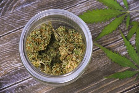 Detail of cannabis buds (scout master strain) on glass jar over wood background - medical marijuana dispensary conceptの写真素材