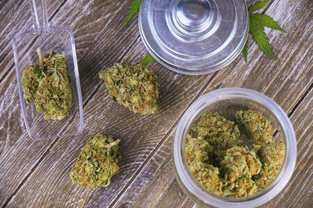 Detail of cannabis buds (scout master strain) on glass jar over wood background - medical marijuana dispensary conceptの写真素材