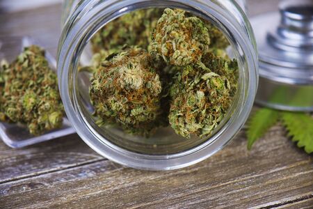 Detail of cannabis buds (scout master strain) on glass jar over wood background - medical marijuana dispensary conceptの写真素材