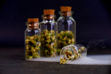 Detail of assorted jars with cannabis calyxes (sour tangie strain) isolated on black background - Medical marijuana dispensary conceptの写真素材