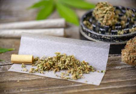 Cannabis joints with rolling paper and grinder over wood backgroundの写真素材