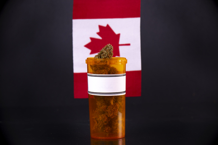 Cannabis bud against canadian flag isolated on black background, medical marijuana conceptの写真素材