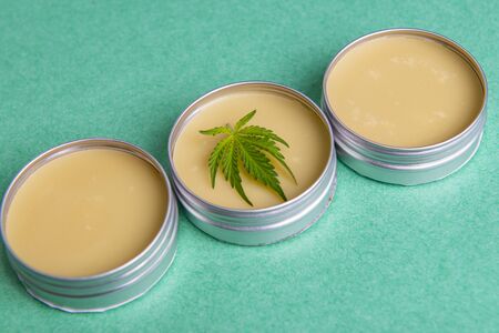 Cannabis salve with hemp and CBD oil and marijuana leaves on green backgroundの写真素材
