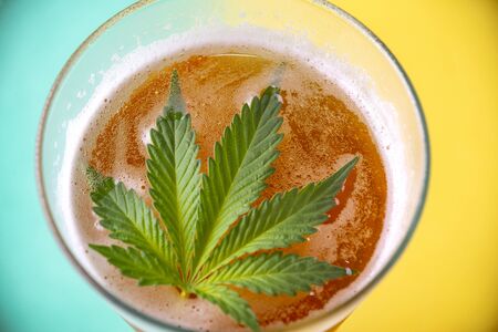Detail of cold glass of beer with cannabis leaf, marijuana infused beverage conceptの写真素材