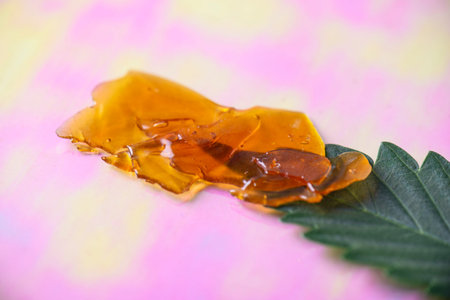 Macro detail of dab tool with cannabis concentrate aka shatter and marijuana leaf, cannabis...