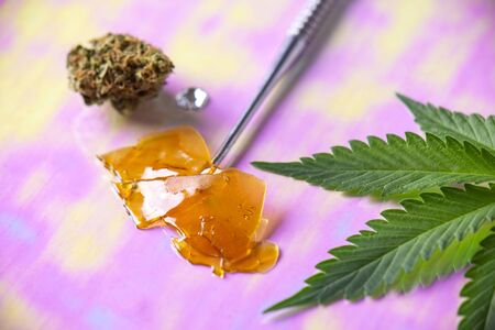 Macro detail of dab tool with cannabis concentrate aka shatter and marijuana leaf, cannabis extraction conceptの写真素材