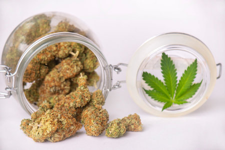 Detail of cannabis buds on clear glass jar isolated on white - medical marijuana dispensary concept