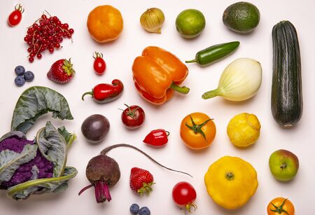 Assorted of fresh fruits and vegetables arranged in a rainbow color pattern over whiate backgroundの写真素材