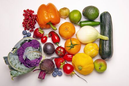 Assorted of fresh fruits and vegetables arranged in a rainbow color pattern over whiate backgroundの写真素材