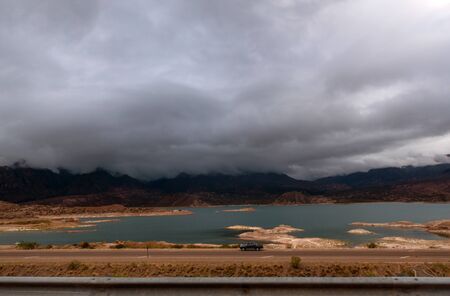 Lake by a road over a cloudy skyの写真素材