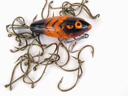 An orange fish shaped lure and fishing hooks over a white backgroundの写真素材