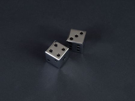 Two metal dice showing a score of seven on a black background.の写真素材