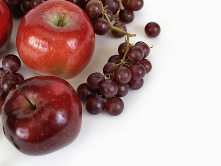 Grapes and apples on a white background. Set to a top corner, with room for text