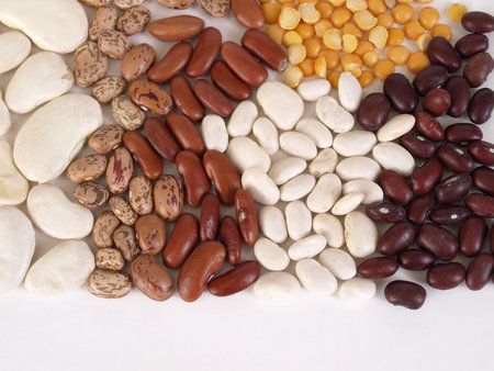 A colorful assortment of various dry beans over a white background with room for text along the...