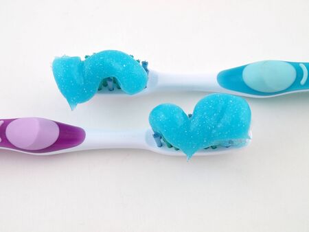 Two toothbrushes with a blue gel toothpaste over a white background.の写真素材